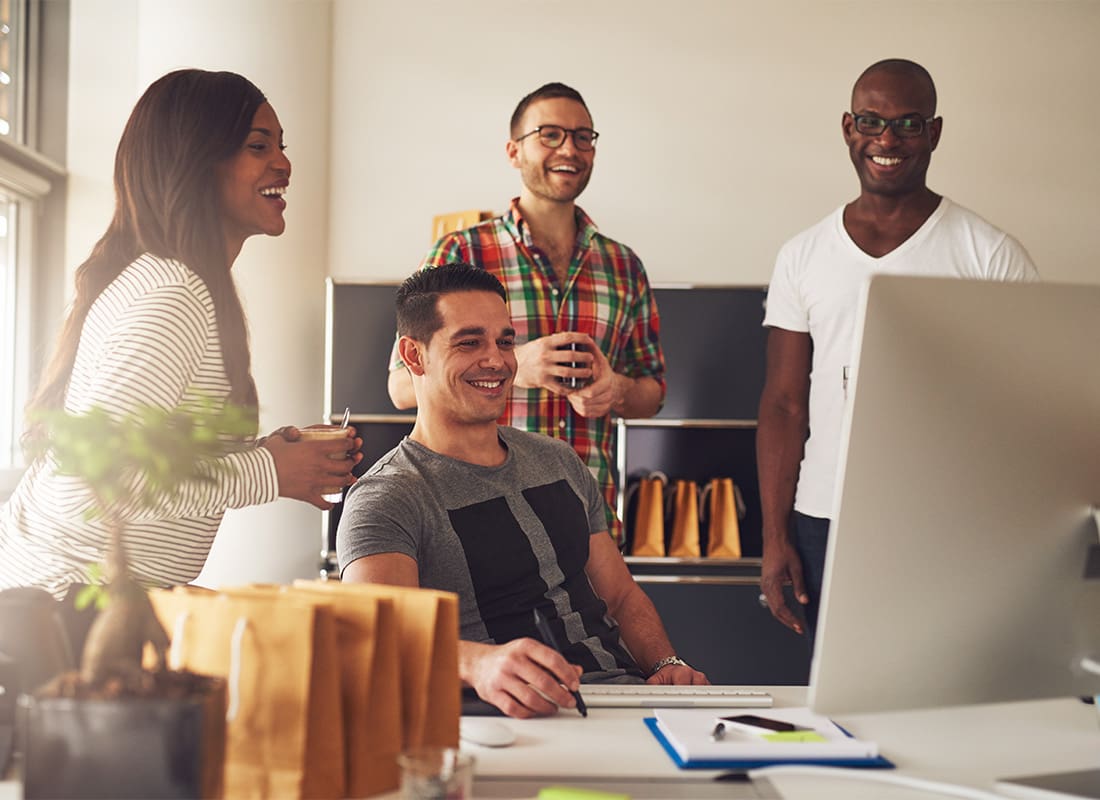 Employee Benefits - Group of Diverse Casual Young Employees Working Together on a Project in a Small Office